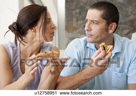 Couple eating together in living room View Large Photo Image Stock Image - Couple eating together in living room. Fotosearch