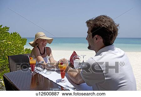 Stock Photo - Couple eating together on deck at beach. Fotosearch