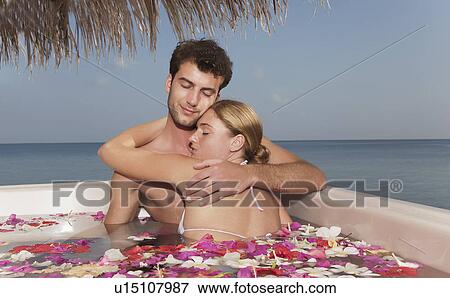 Couple embracing in pool with petals View Large Photo Image Stock Photo - Couple embracing in pool with petals. Fotosearch