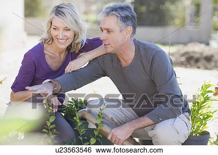 Stock Photograph - Couple examining garden together. Fotosearch