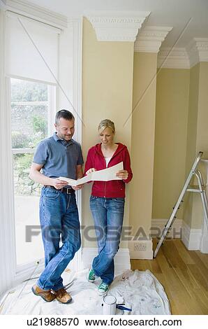 Stock Image - Couple examining plans in new home. Fotosearch