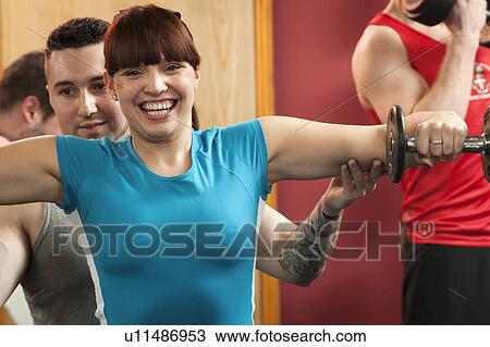 Stock Image - Couple exercising in gym together. Fotosearch