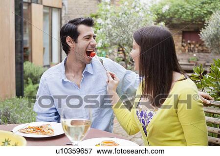 Couple feeding each other outdoors View Large Photo Image Stock Photo - Couple feeding each other outdoors. Fotosearch