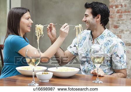 Stock Photo - Couple feeding each other spaghetti. Fotosearch