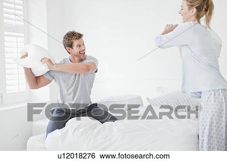 Couple having a pillow fight in bedroom View Large Photo Image Stock Photograph - Couple having a pillow fight in bedroom. Fotosearch