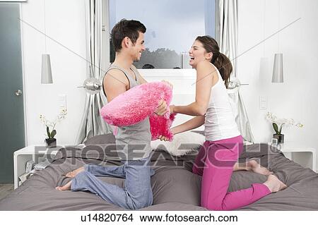 Couple having a pillow fight View Large Photo Image Picture - Couple having a pillow fight. Fotosearch