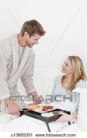 Stock Image - Couple having breakfast in bed. Fotosearch