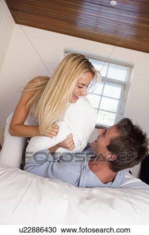 Couple having pillow fight in bed View Large Photo Image Stock Image - Couple having pillow fight in bed. Fotosearch