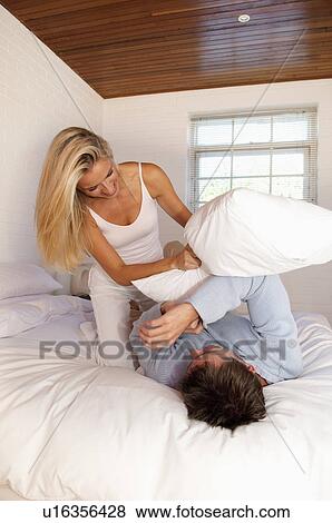 Stock Photo - Couple having pillow fight in bed. Fotosearch