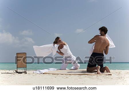 Couple having pillow fight on beach View Large Photo Image Stock Photo - Couple having pillow fight on beach. Fotosearch
