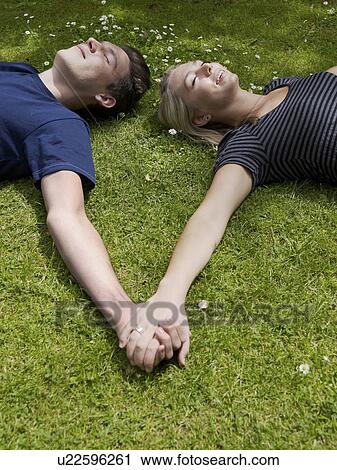 Couple holding hands in grass View Large Photo Image Stock Image - Couple holding hands in grass. Fotosearch