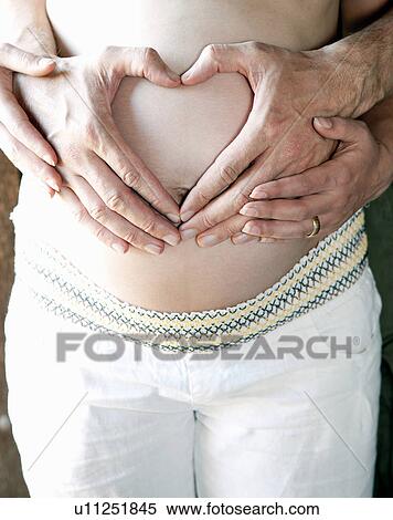 Stock Photography - Couple holding woman's pregnant belly. Fotosearch