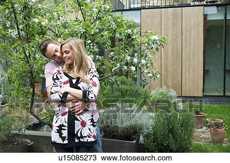 Stock Image - Couple hugging in backyard. Fotosearch
