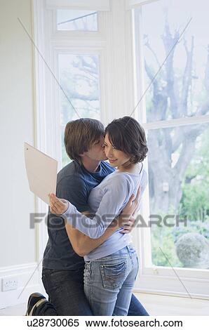 Stock Photography - Couple hugging in front of window. Fotosearch