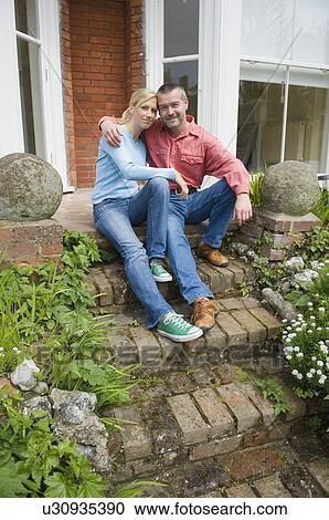 Stock Image - Couple hugging on back porch steps. Fotosearch