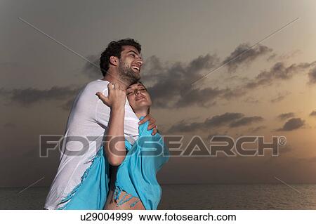 Couple hugging on beach at sunset View Large Photo Image Stock Photo - Couple hugging on beach at sunset. Fotosearch
