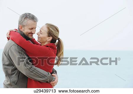 Stock Image - Couple hugging on beach. Fotosearch