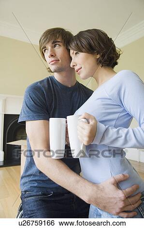 Stock Photograph - Couple hugging with coffee in new home. Fotosearch