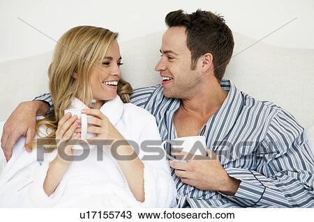Stock Image - Couple in bathrobes drinking coffee. Fotosearch