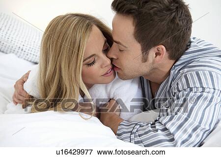 Stock Photo - Couple in bathrobes kissing on bed. Fotosearch