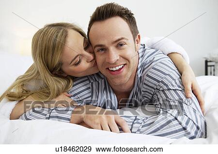 Stock Photo - Couple in bathrobes kissing on bed. Fotosearch
