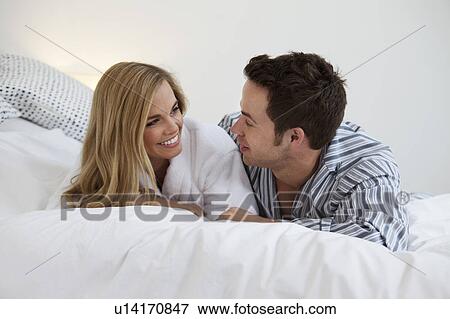 Couple in bathrobes laying on bed View Large Photo Image Stock Photo - Couple in bathrobes laying on bed. Fotosearch