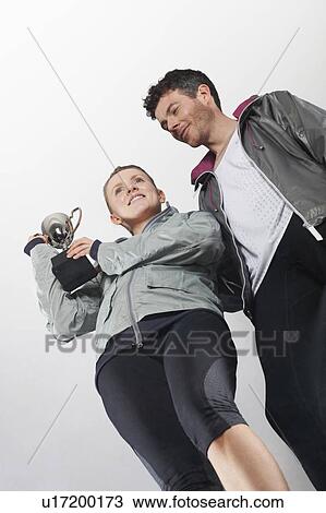 Stock Image - Couple in running gear holding trophy. Fotosearch