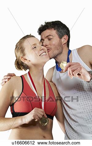 Stock Image - Couple in running gear wearing medals. Fotosearch