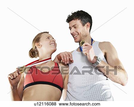 Stock Photo - Couple in running gear wearing medals. Fotosearch
