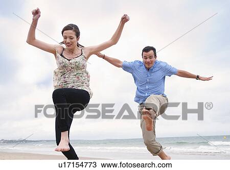 Couple jumping on beach View Large Photo Image Stock Image - Couple jumping on beach. Fotosearch