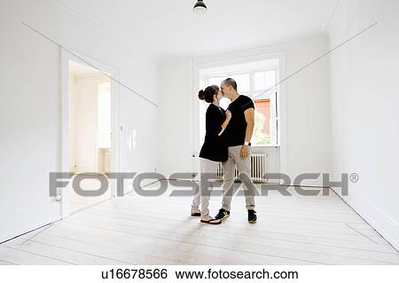 Stock Photograph - Couple kissing in new home. Fotosearch