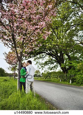 Stock Image - Couple kissing on rural road. Fotosearch