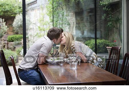 Stock Photo - Couple kissing over meal at home. Fotosearch