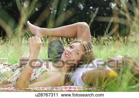 Stock Image - Couple laying in field together. Fotosearch