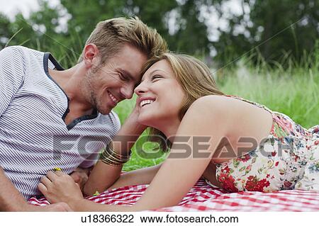 Stock Image - Couple laying on picnic blanket. Fotosearch