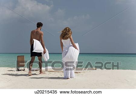 Stock Photography - Couple making bed on tropical beach. Fotosearch