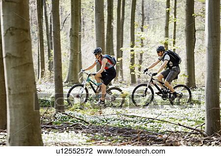 Stock Image - Couple mountain biking together. Fotosearch