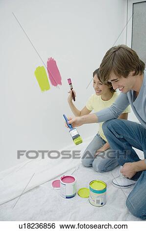 Couple painting together in new home View Large Photo Image Stock Photograph - Couple painting together in new home. Fotosearch