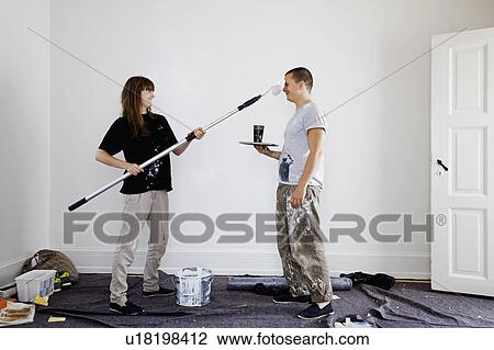 Couple painting walls of new home View Large Photo Image Stock Image - Couple painting walls of new home. Fotosearch