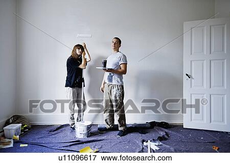 Stock Photo - Couple painting walls of new home. Fotosearch