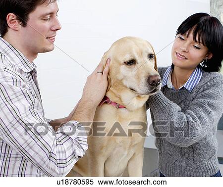Stock Photography - Couple petting a dog together. Fotosearch