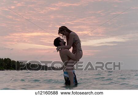 Couple playing in water at beach View Large Photo Image Stock Photo - Couple playing in water at beach. Fotosearch