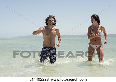 Couple playing in water at beach View Large Photo Image Stock Photo - Couple playing in water at beach. Fotosearch