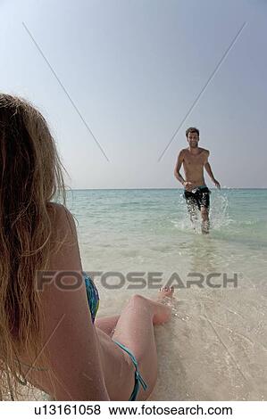 Couple playing in water on beach View Large Photo Image Stock Photo - Couple playing in water on beach. Fotosearch