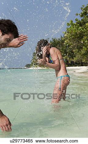 Stock Photography - Couple playing in water on beach. Fotosearch