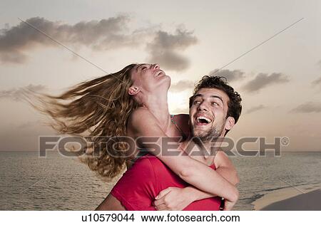 Picture - Couple playing on beach at sunset. Fotosearch