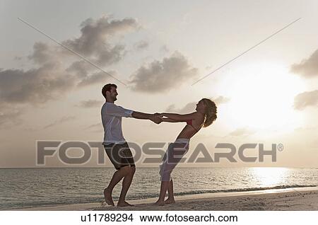 Picture - Couple playing on beach at sunset. Fotosearch