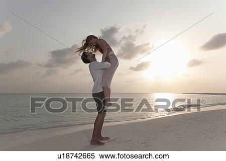 Stock Photography - Couple playing on beach at sunset. Fotosearch