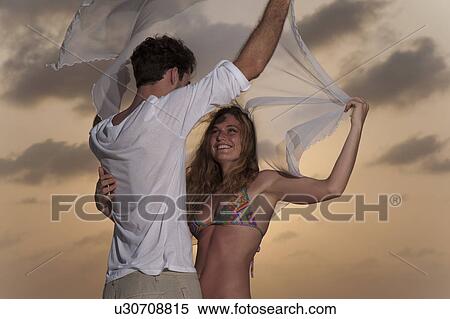 Stock Photography - Couple playing on beach at sunset. Fotosearch