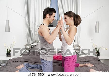 Stock Image - Couple playing on bed together. Fotosearch
